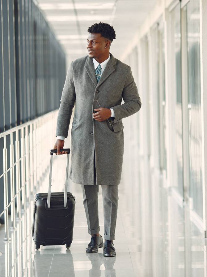 Black man at the airport. Guy with suitcase. Male in a black suit.